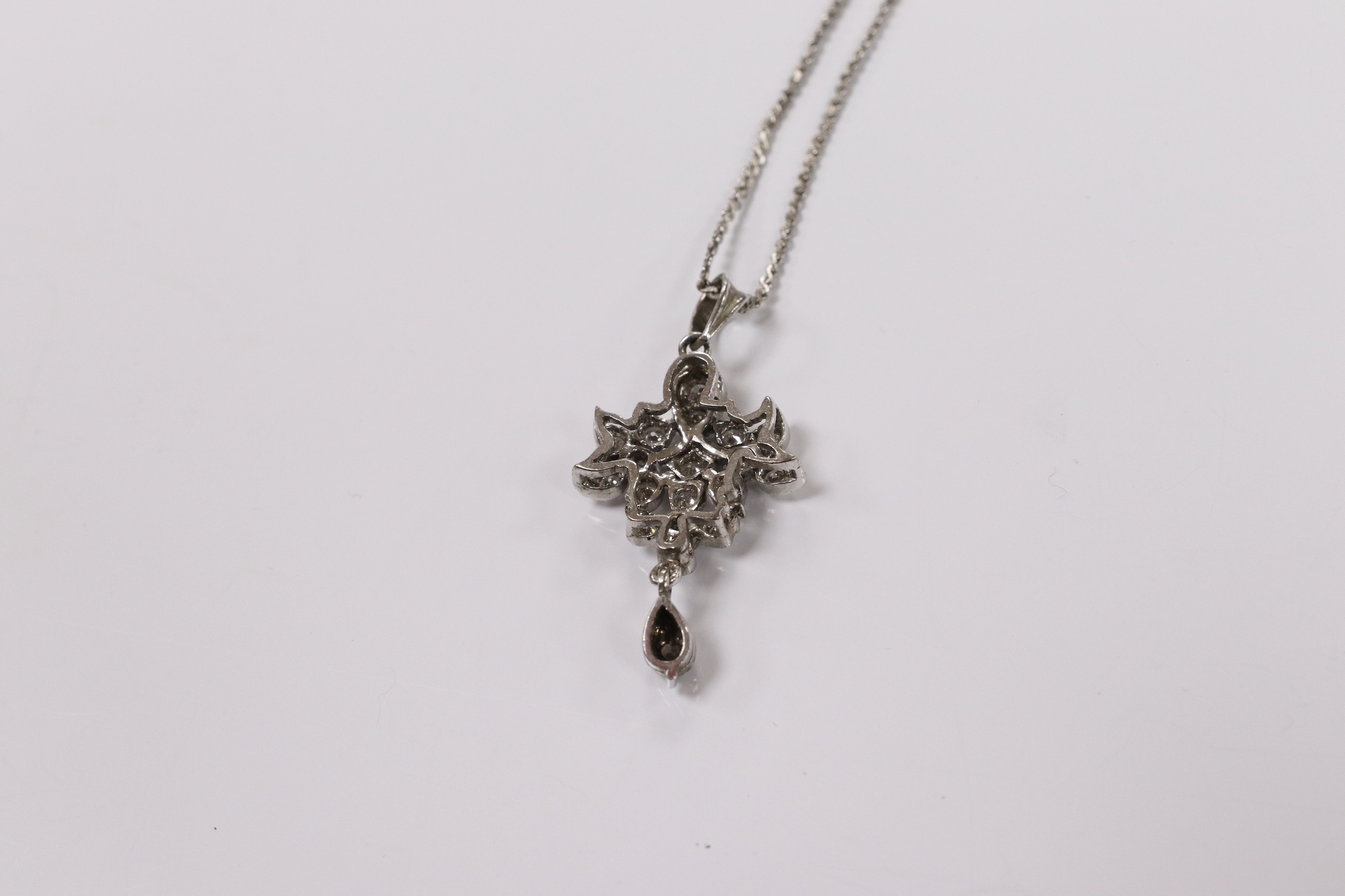 A modern white metal and diamond chip cluster set drop pendant, 33mm, on a base metal chain. Condition - fair